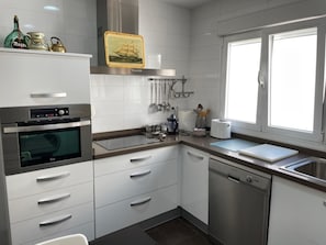 Eine moderne Küche mit weißen Schränken, Edelstahlgeräten und einem Fenster, das für natürliches Licht sorgt.