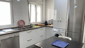 Una cocina moderna con electrodomésticos de acero inoxidable, lavavajillas y lavadora.