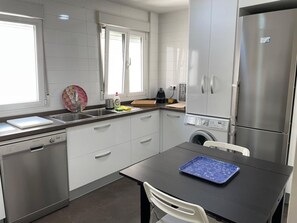 Eine moderne Küche mit Edelstahlgeräten, einem Geschirrspüler und einer Waschmaschine.