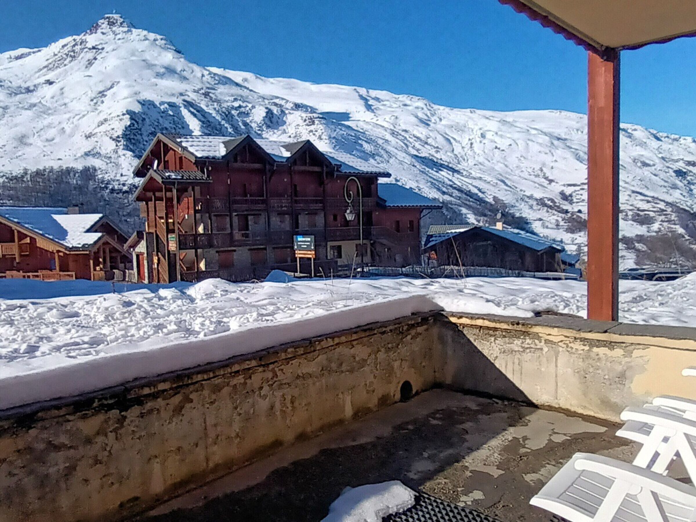 Une montagne enneigée sur laquelle se trouve un bâtiment en bois doté d’un balcon et d’une enseigne.