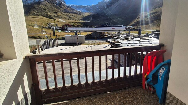 Ein Balkon mit Blick auf eine Berglandschaft, einem Bollin- und Tignes-Schild und einem roten Stuhl.