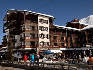 Ein mehrstöckiges Hotel mit Balkonen, einem zentralen Turm und Außenbereichen zum Sitzen.