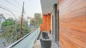 Un balcón con dos sillas, una mesita y vista a la calle y edificios.