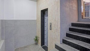 Un interior moderno con una pared de mármol, una puerta y una escalera.