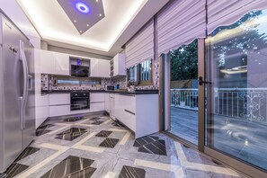 Eine moderne Küche mit einer großen Kochinsel, einem eingebauten Backofen und einer Glastür zum Balkon.