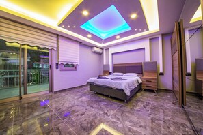 A modern bedroom with a bed, a nightstand, a dresser, and a balcony with glass doors.