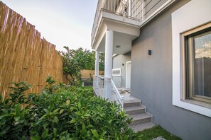 A building with a grey exterior, white columns, a balcony, and a wooden fence. - Daisy Villa Icmeler Marmaris Private (Marmaris)