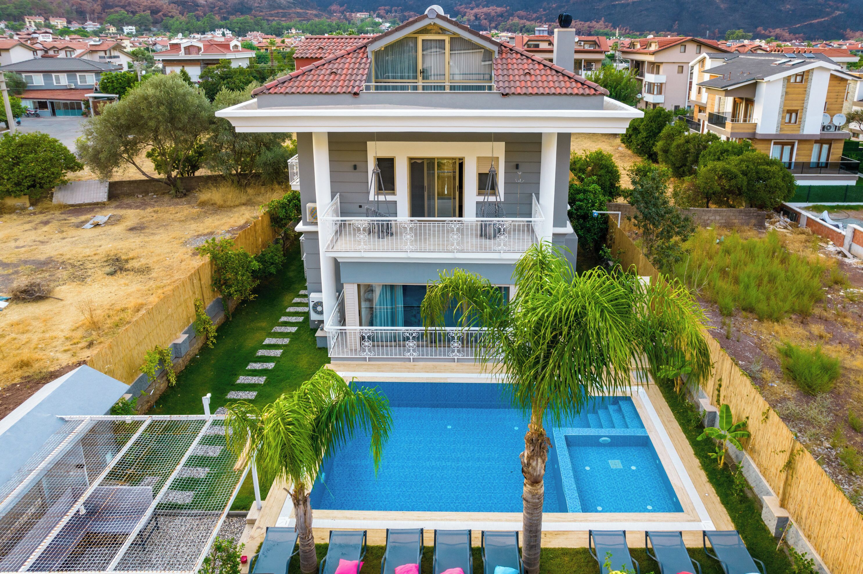 A two-story house with a swimming pool, a balcony, and a view of the surrounding neighborhood.