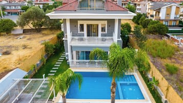 A two-story house with a swimming pool, a balcony, and a view of the surrounding neighborhood.