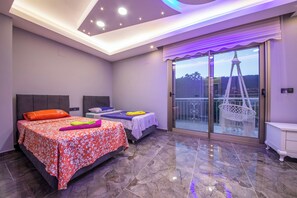 A bedroom with two beds, a balcony with a view of a tower, and a modern ceiling design.