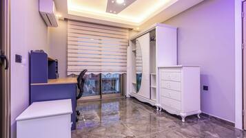 A modern room with a desk, wardrobe, and a large window with blinds.