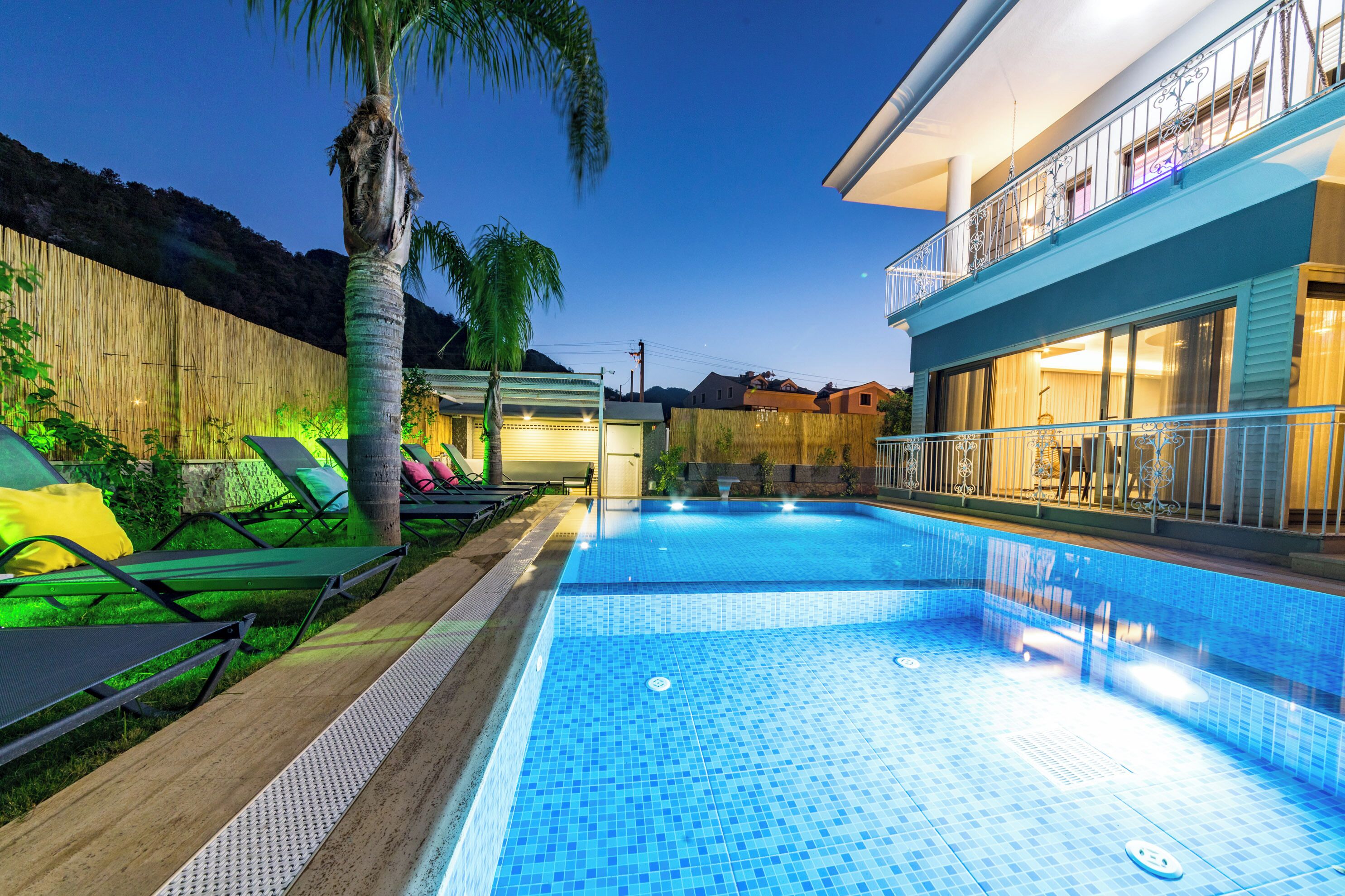 Piscina com espreguiçadeiras e cerca de madeira.