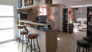 A kitchen with a microwave, stove, and bar stools. - Family house with pets - 8 guests (Le Palais)