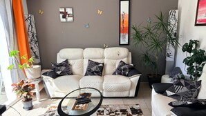 A living room with a sofa, a coffee table, and decorative pillows. - Family house with pets - 8 guests (Le Palais)