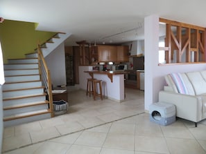 Ein geräumiger Wohnbereich mit Küche, einer Treppe und einem Platz für Haustiere.