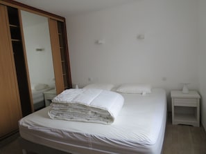 Ein Schlafzimmer mit einem Bett, einem Nachttisch, einem Schrank und einem Holzschrank.