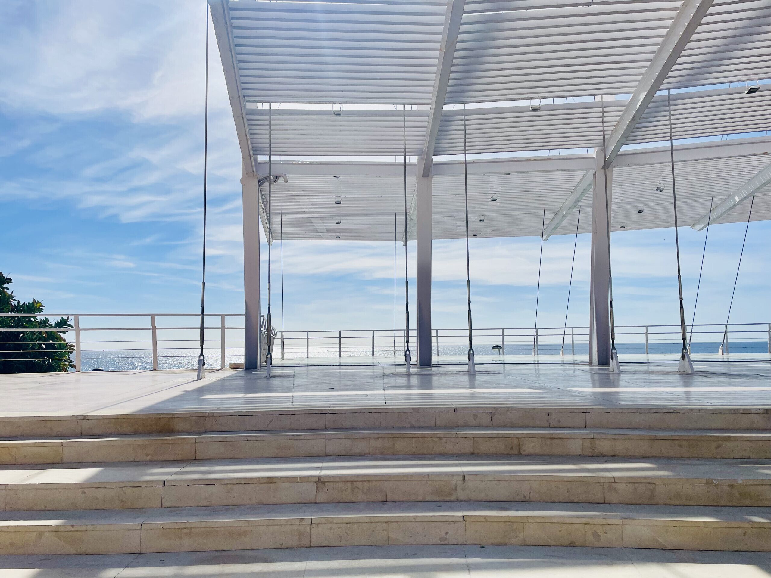 A covered outdoor area with steps leading to a railing overlooking a body of water.