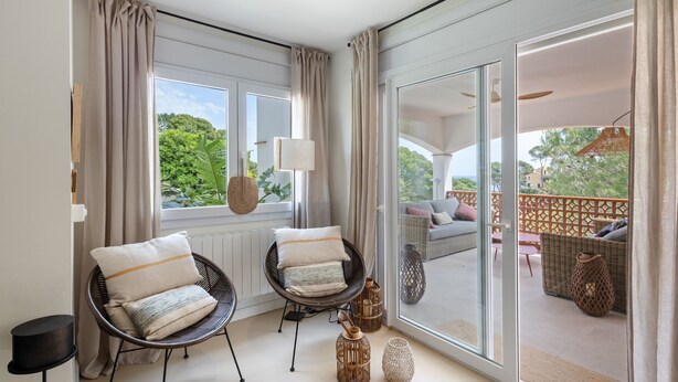 A room with two wicker chairs, a lamp, and a view of an outdoor seating area. - Villa with Pool Just 500 Meters from the Beach (Begur)