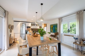 A modern kitchen with a wooden island, pendant lights, and a view of the outdoors. - Villa with Pool Just 500 Meters from the Beach (Begur)
