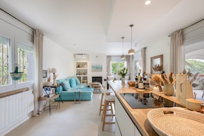 A modern kitchen with a central island, bar stools, and a dining area with a blue sofa. - Villa with Pool Just 500 Meters from the Beach (Begur)