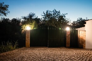 A gated entrance with a cobblestone driveway leading to a building with a stone wall. - Casa Da Maria Tereza - Villa with Pool and Sauna (Tavira)