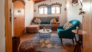A cozy living room with a sofa, a teal armchair, a coffee table, and a patterned rug.