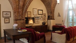 Um quarto com um arco de tijolos, televisão, mesa de jantar e lareira.