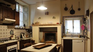 Uma cozinha com lareira, armários de madeira, uma mesa de jantar e uma máquina de lavar louça.