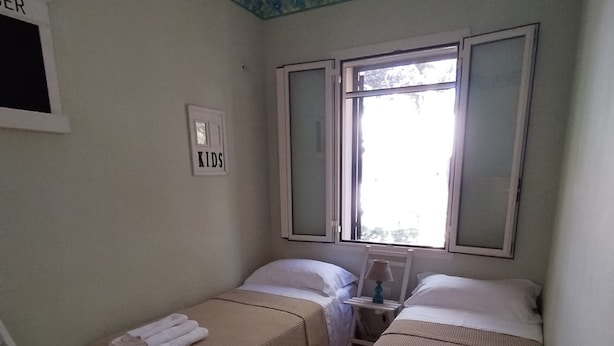 Una habitación con dos camas, una ventana, una mesita y una silla.
