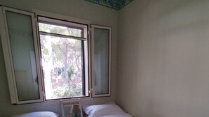 Una habitación con dos camas, una ventana y una mesita de noche con lámpara.