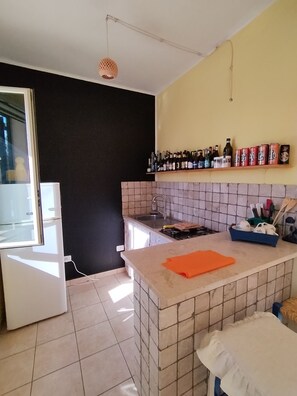 A kitchen with a tiled backsplash, a countertop, a sink, and a refrigerator. - Apartment in pine forest with sea view. Located in the natural park of Porto selvaggio (Nardò)