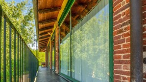 A covered outdoor corridor with glass walls, brick walls, and a metal fence.