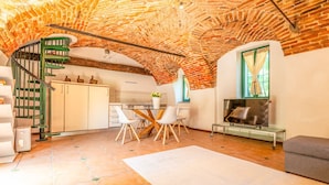 Ein großzügiger Wohnbereich mit Ziegeldecke, einem Esstisch mit Stühlen, einer Couch und einem Kamin.
