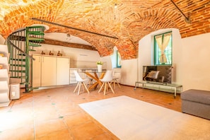A spacious living area with a brick ceiling, a dining table with chairs, a sofa, and a fireplace. - Cristal Apartments - Green Apartment (Masserano)
