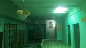 A hallway with a chandelier, a door with a poster, and a patterned floor. - Yashoda Kunj (Mathura)