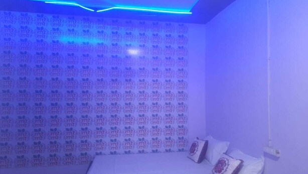A bedroom with a patterned wall, a bed with pillows, and blue LED lighting. - Yashoda Kunj (Mathura)