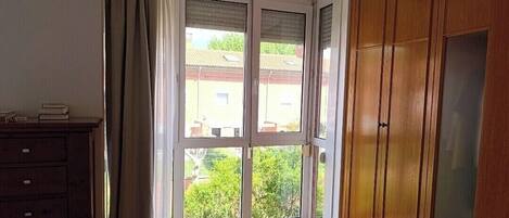 Ett rum med en stor skjutdörr av glas, en garderob i trä och en byrå.