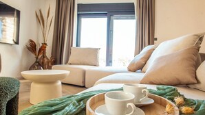 A cozy room with a sofa, a small table, and a tray with cups. - Villa Orkula Rab with Heated Pool, Gym & Sea View (Rab)