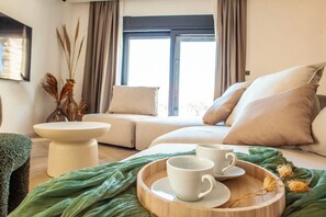 Ein gemütliches Zimmer mit einer Couch, einem kleinen Tisch und einer Ablage mit Tassen.