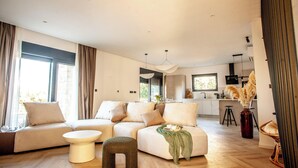 A modern living room with a sofa, ottoman, and coffee table. - Villa Orkula Rab with Heated Pool, Gym & Sea View (Rab)