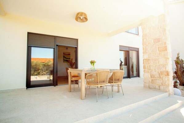 A patio with a table and chairs, a stone wall, and a sliding glass door.