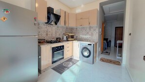 A compact kitchen with a refrigerator, stove, oven, and washing machine.