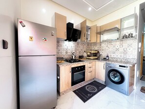 A modern kitchen with stainless steel appliances, wooden cabinets, and patterned backsplash tiles. - Belvara luxe pause (Beni Mellal)