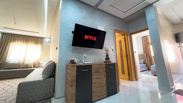 A modern living room with a flat-screen TV, a sofa, a cabinet, and a decorative vase.
