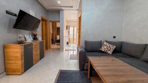 A modern living room with a sofa, a coffee table, and a TV mounted on the wall.