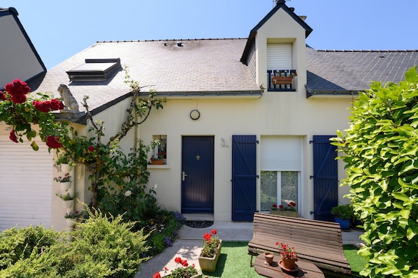 A two-story house with a front door, a small balcony, and a garden with flowers and plants. - Guest Room 'Couette Et Café' with Shared Garden and Wi-Fi (Arradon)
