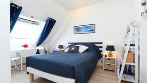 Un dormitorio ordenado con cama, escritorio, silla, lámpara y estantería.