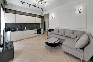 Een moderne keuken met een ingebouwde oven, een eethoek met een ronde tafel en een grijze bank.
