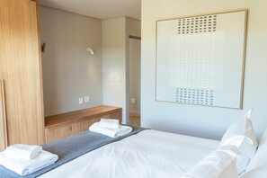 Ein Hotelzimmer mit Bett, einer Holzbank, einer Wandleuchte und einem gerahmten Kunstwerk.