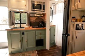 A compact kitchen with a microwave, stove, and cabinets.